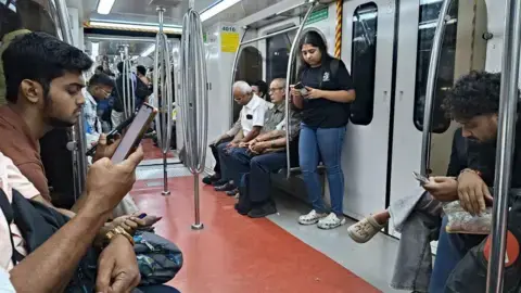 عکس از NurPhoto از طریق Getty Images؛ مردم در حال بررسی تلفن‌های هوشمند خود درون قطار مترو در کلکات